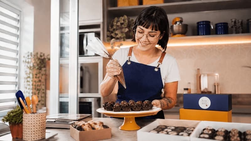 Imagem de mulher preparando brigadeiros em casa